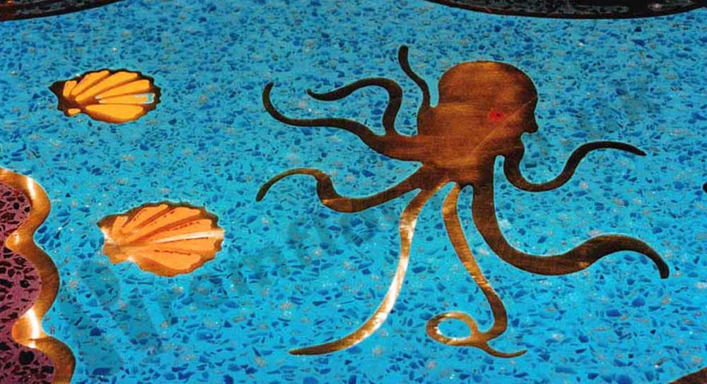 Sea creatures and shells cut from brass in a blue resin terrazzo bar top
