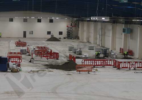 Factory in the middle of refurbishment showing floor tiles being laid, screed on floor and barriers dividing areas